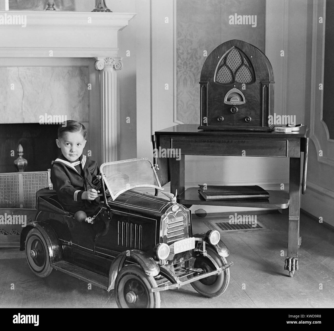 Kleinen Jungen in seinem Spielzeug Automobil neben einem Stand der Technik Atwater Kent Radio. Das Radio verfügt über Lautsprecher eingeschlossen hinter dem Stoff Öffnungen im eleganten Gehäuse abgedeckt (BSLOC 2016 10 59) Stockfoto