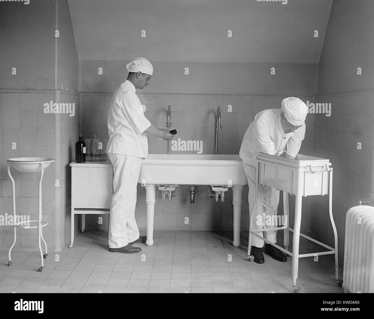 Chirurg und Anästhesist sorgfältig waschen ihre Hände und Unterarme in spezialisierten sinkt. Vor Antibiotika postoperative Infektion war Anlass zu ernster Besorgnis. 1922 in einem Krankenhaus in Washington, D.C. (BSLOC 2016 10 31) Stockfoto