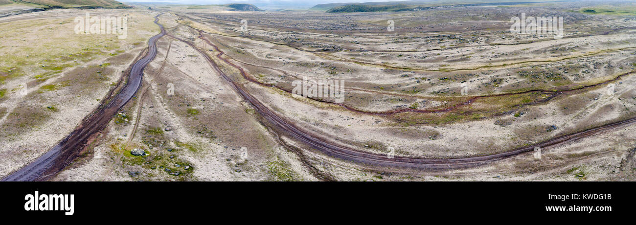 Luftbild mit Blick auf eine Ebene mit vielen Schluchten und eine unbefestigte Straße an der Basis der Vulkan Cotopaxi in der ecuadorianischen Anden. Stockfoto