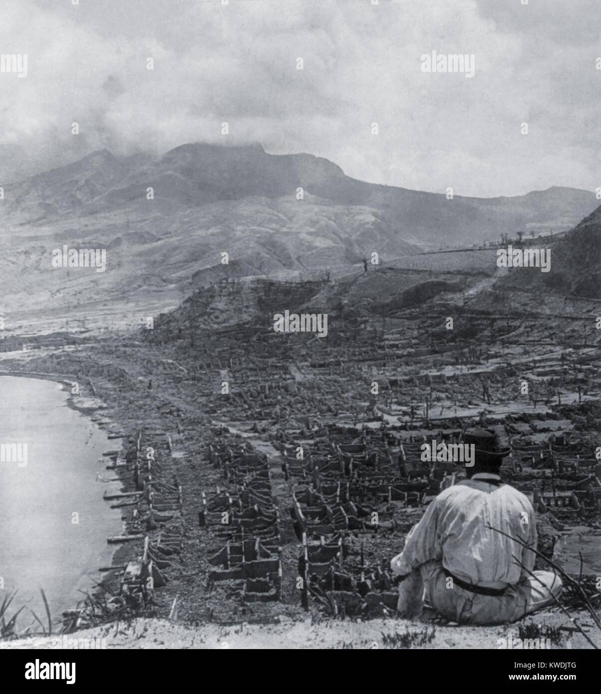 Mann auf das Orange Hill schaut über die tote Stadt St. Pierre und bis zu dampfenden Vulkan, Mont Pelee. Eine Glutlawine ums leben 30.000 Menschen in der Küstenstadt am 8. Juni 1902. Mont Pelee betrug 4.500 Fuß in der Höhe und ca. 6 km nach Norden (BSLOC 2017 17 63) Stockfoto