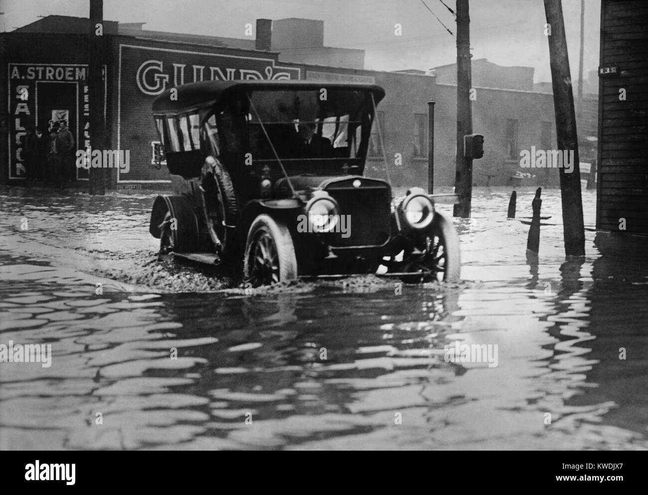 Ein Automobil fährt durch Axel hoch Wasser auf einem überfluteten Cleveland Street, wahrscheinlich im Jahr 1913. Die frühe Autos wurden mit hohen Abstände die rauen Straßen der Zeit zu navigieren. Die grosse Flut von 1913 war Ohios größte Wetter Katastrophe des frühen 20. Jahrhunderts (BSLOC 2017 17 95) Stockfoto