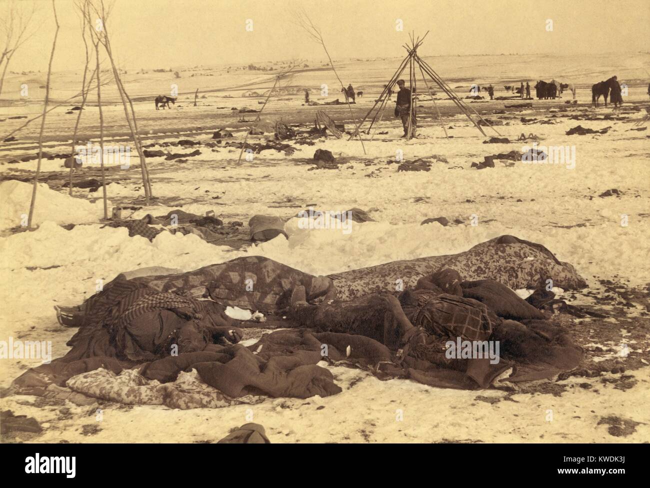 Mehrere Tote Lakota Sioux sind in Decken nach dem Wounded Knee Massaker von Dez. 29, 1890 gewickelt. Körper lag auf dem Boden nach dem Schießen, bis gesammelt und durch Leiharbeiter begraben Anfang Januar 1891. In der Ferne, mehr Körper sind, Frames ihre Tipis, und Soldaten (BSLOC 2017 18 22) Stockfoto