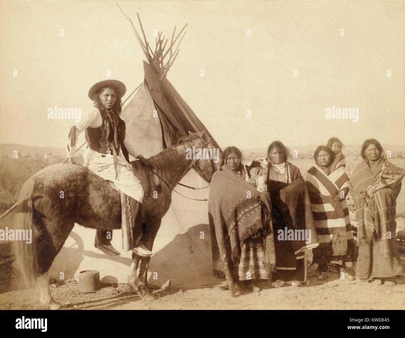 Lakota Frauen, drei mit Babys Kleinkinder in Hängegestelle und a Lakota Mann auf dem Pferd. Foto auf Pine Ridge Reservat nach dem Wounded Knee Massacre. Foto von John Grabill, Jan. 1891 (BSLOC 2017 18 35) Stockfoto