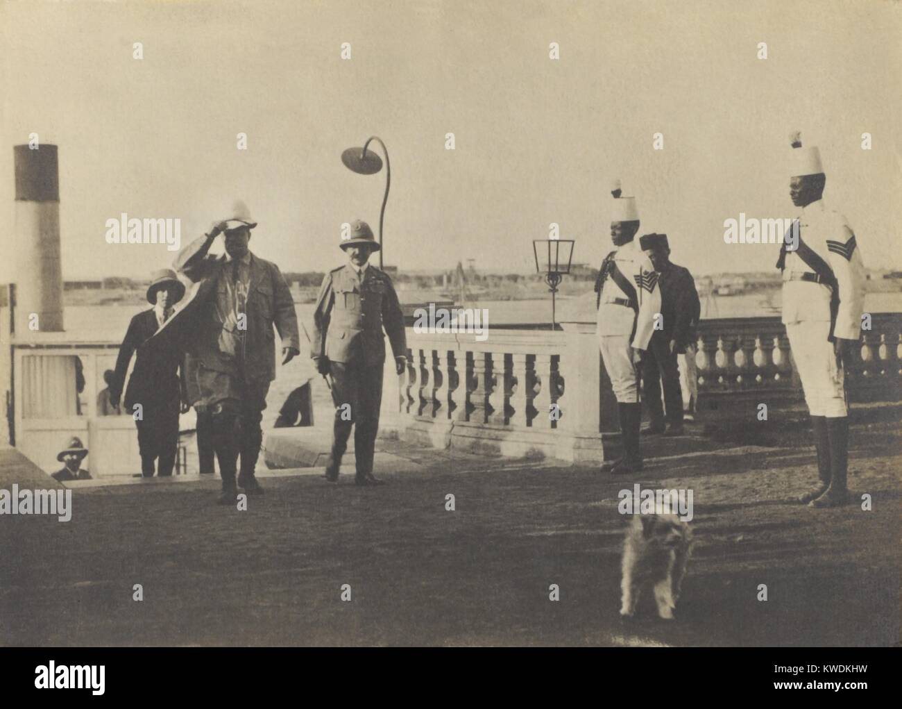 Theodore Roosevelt Anreise mit Sohn Kermit, in Khartum, Sudan, 13. März 1910. Nach dem Verlassen des Schiffes, die Sie auf dem Nil gesegelt, werden sie von einem örtlichen Beamten mit zwei Schutzvorrichtungen (BSLOC 2017 8 15 begleitet) Stockfoto
