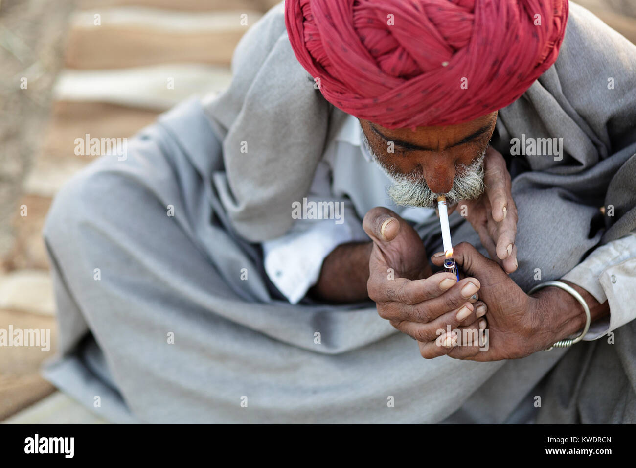 Szene in Pushkar Camel Fair, Mann im roten Turban eine Zigarette, Ajmer, Pushkar, Rajasthan, Indien Stockfoto