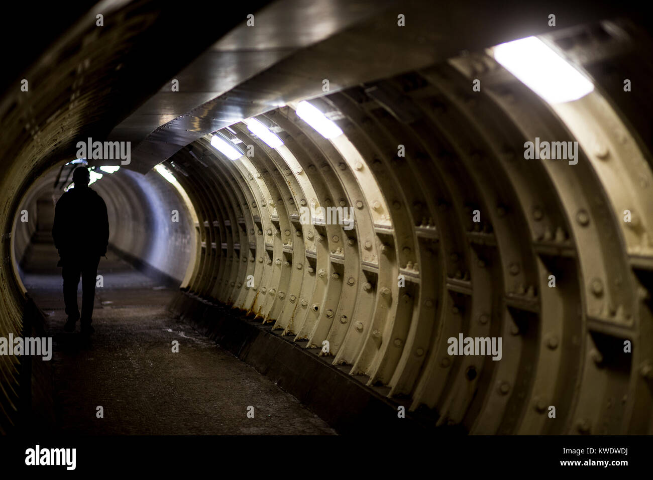 Eine schattenhafte figue Spaziergänge in die Greenwich Foot Tunnel, Greenwich, London Stockfoto