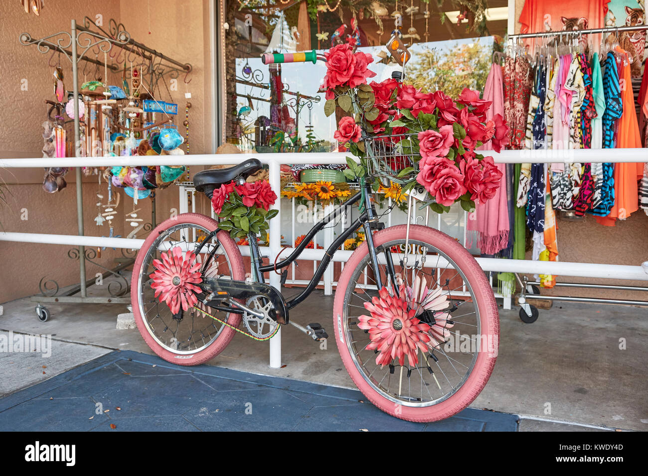 Woman's Fahrrad rosa lackiert und mit roten Blumen sitzt vor einem kleinen Laden, in Tarpon Springs, Florida, USA. Stockfoto