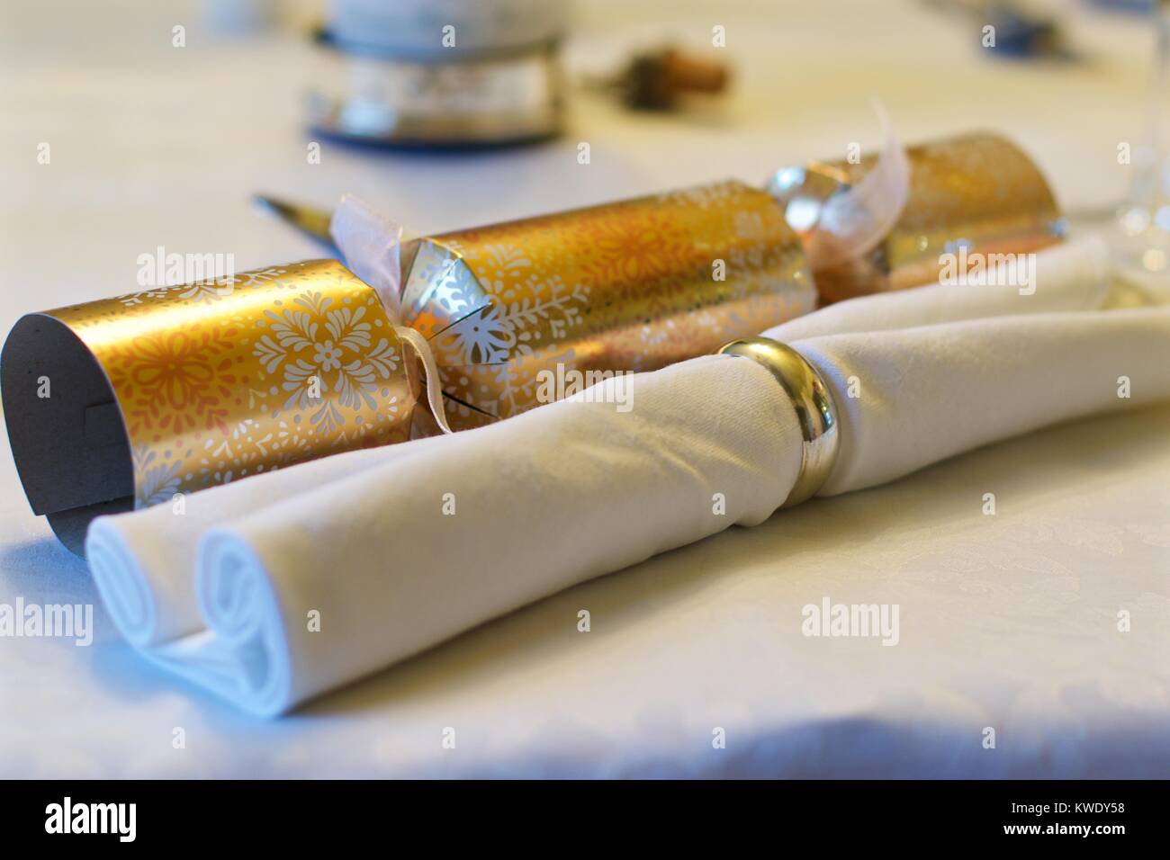 Christmas Cracker neben weißen Serviette eine Serviette auf einem weißen Tischtuch zu Weihnachten, Großbritannien Stockfoto