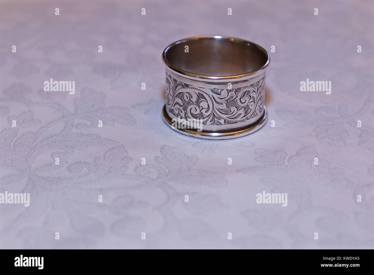 Kunstvolle Servietten Ring auf einem weiß-gemusterte Tischdecke Stockfoto