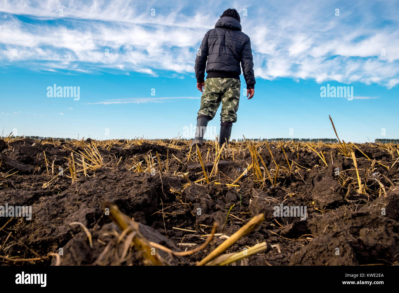 Low Angle View der Mann mit Kapuzenjacke beim Stehen auf Feld gegen bewölkter Himmel Stockfoto