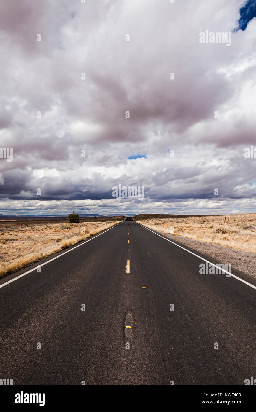 Country Road inmitten von Feld gegen stürmische Wolken Stockfoto