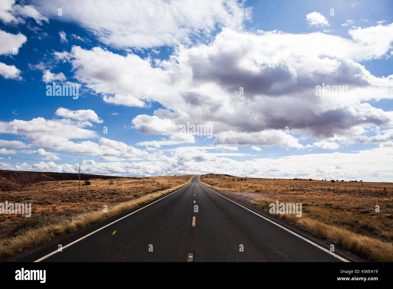 Landstraße inmitten Feld gegen bewölktem Himmel Stockfoto