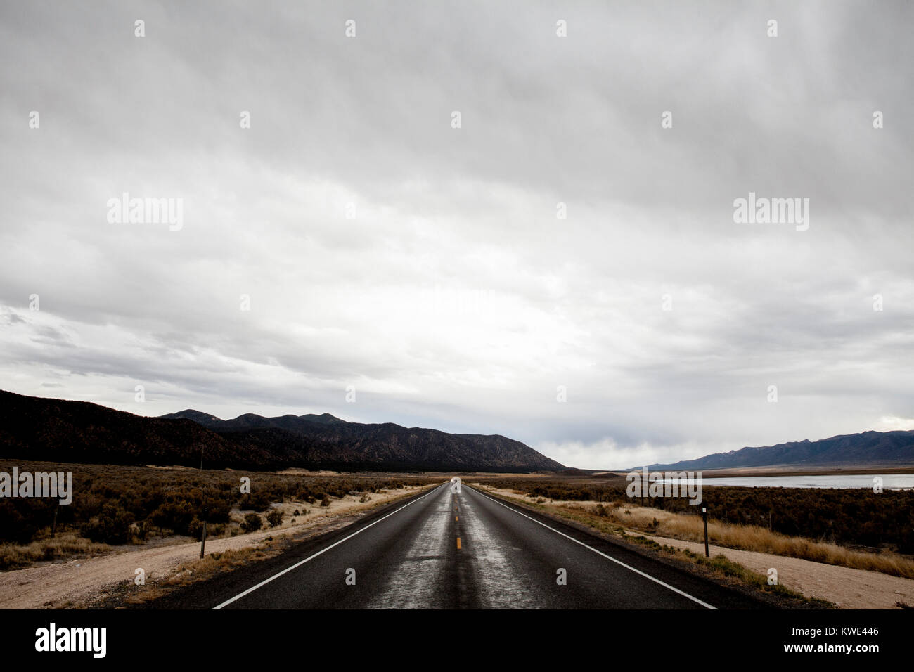 Country Road inmitten von Feld gegen Berge und bewölkter Himmel Stockfoto
