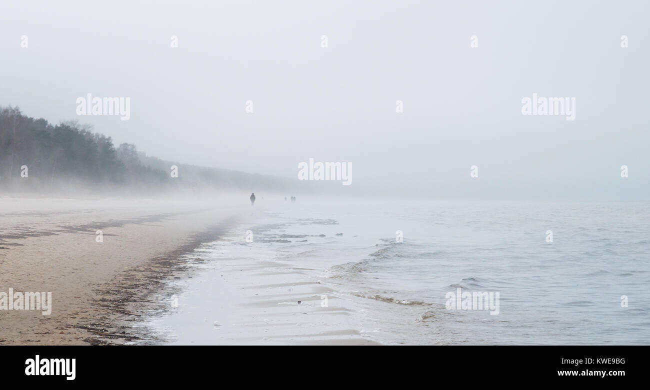 Eine kalte Szene an einem Strand in Jurmala mit wenigen Menschen zahlen in der Ferne und starker Nebel rollen in vom Meer. Stockfoto