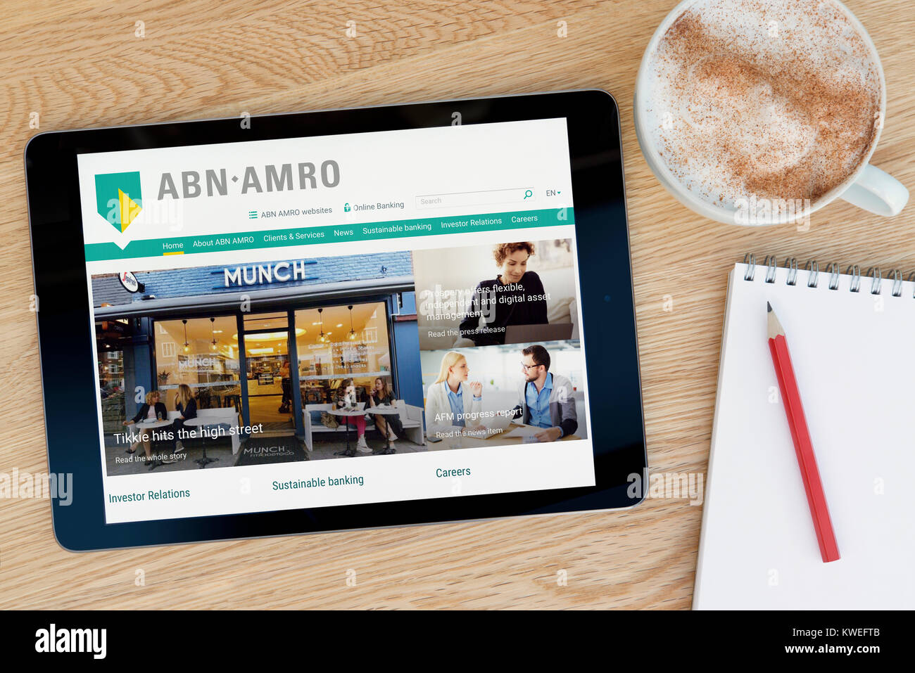 Die ABN AMRO Webseite auf einem iPad tablet device, ruht auf einem hölzernen Tisch neben einem Notizblock, Bleistift und Tasse Kaffee (nur redaktionell) Stockfoto