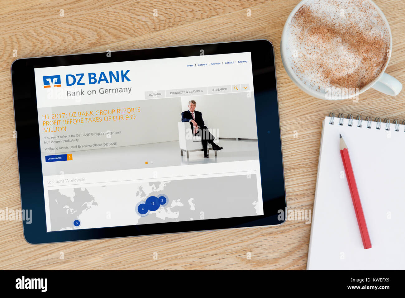Die DZ Bank Website auf einem iPad tablet device, ruht auf einem hölzernen Tisch neben einem Notizblock, Bleistift und Tasse Kaffee (nur redaktionell) Stockfoto