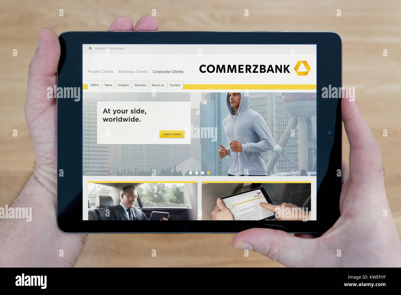 Ein Mann schaut auf der Internetseite der Commerzbank auf seinem iPad tablet device, Schuß gegen einen hölzernen Tisch top Hintergrund (nur redaktionelle Nutzung) Stockfoto