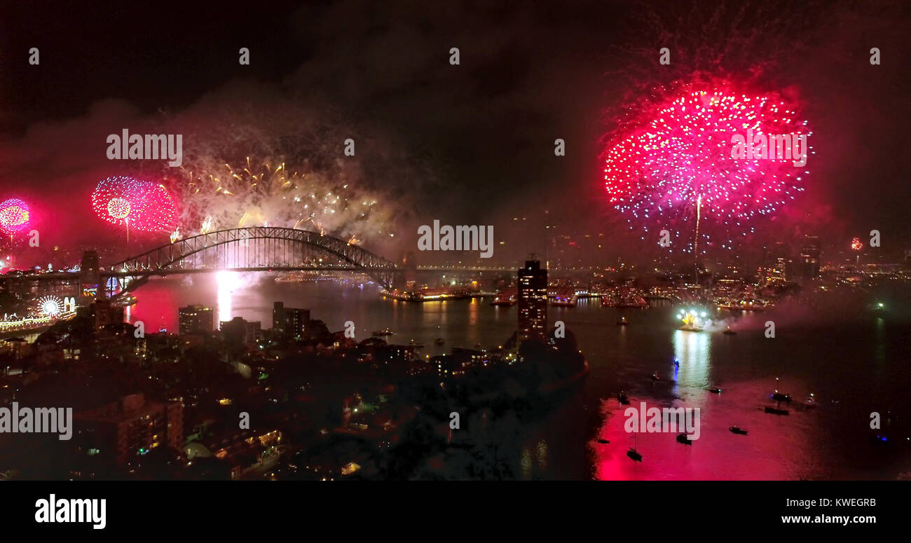 Neues Jahr 2018 Feuerwerk in Sydney, Australien, um Mitternacht. Leuchtend rote Kugeln leuchten CBD Grenzsteine um Sydney Harbour und reflektieren in verschwommen Stockfoto