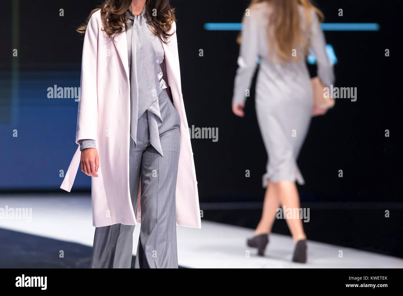 Zwei weibliche Modelle gehen Sie die Start- und Landebahn in verschiedenen Kleider während einer Modenschau. Fashion Catwalk Ereignis zeigt neue Sammlung von Kleidung. Stockfoto