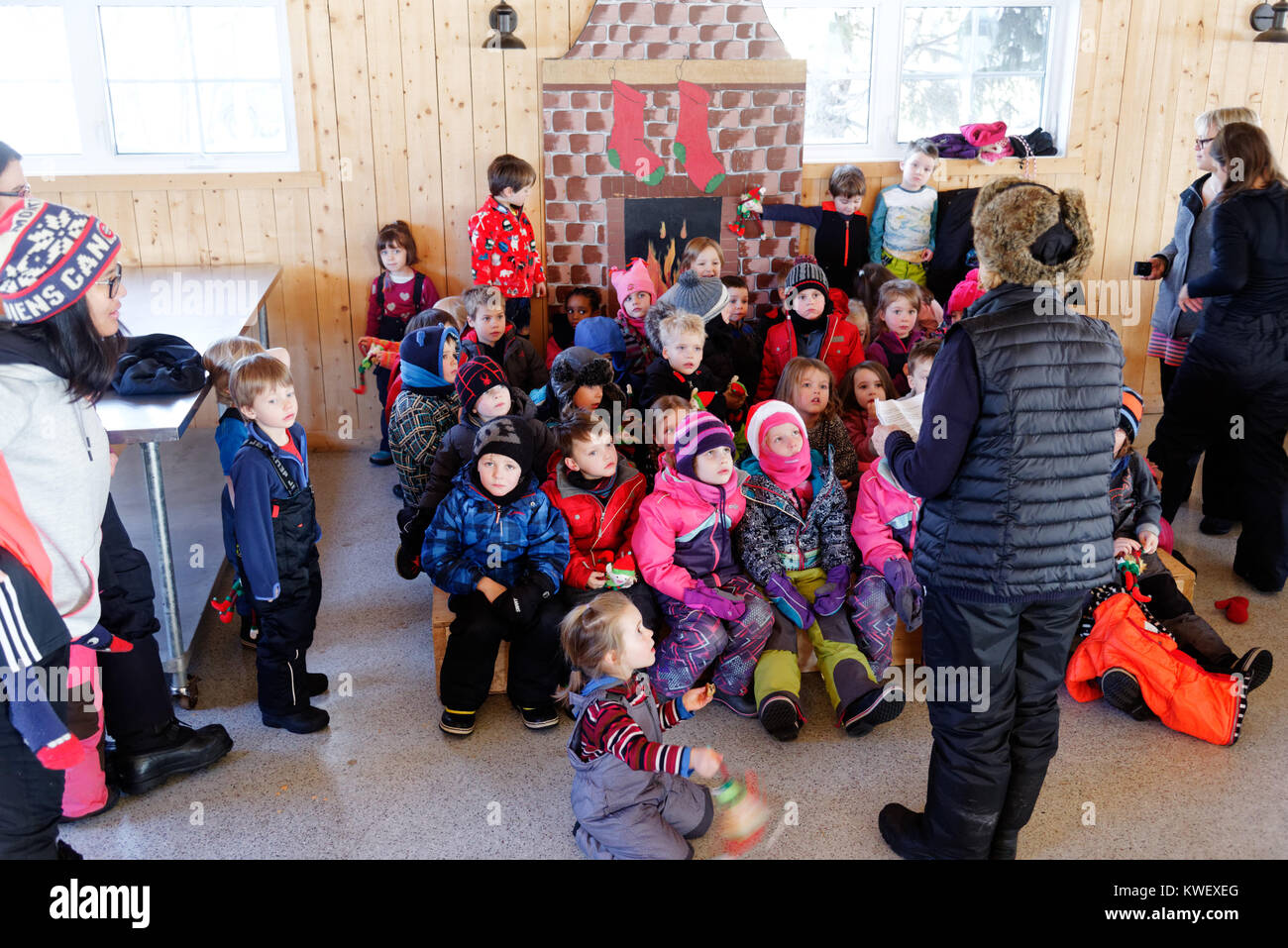 Eine Gruppe junger Kinder aufmerksam zuhören zu einer Geschichte, Winter in Québec. Die Kinder sind gekleidet. Stockfoto