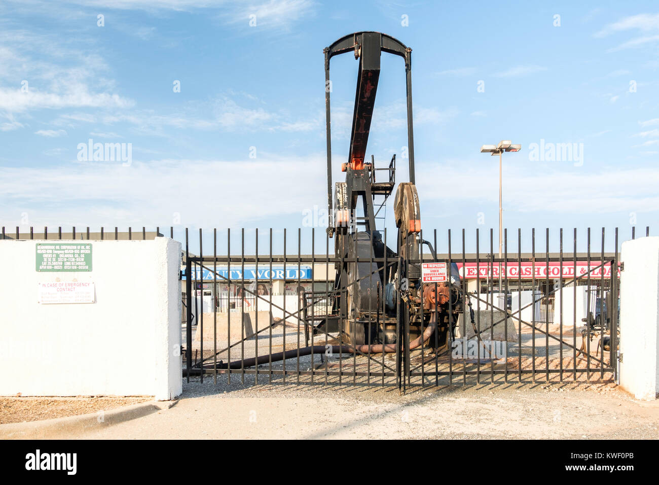 Eine Pumpe jack Ölförderung in der Mitte von einem Parkplatz in einem Einkaufszentrum in Oklahoma City, Oklahoma, USA. Stockfoto