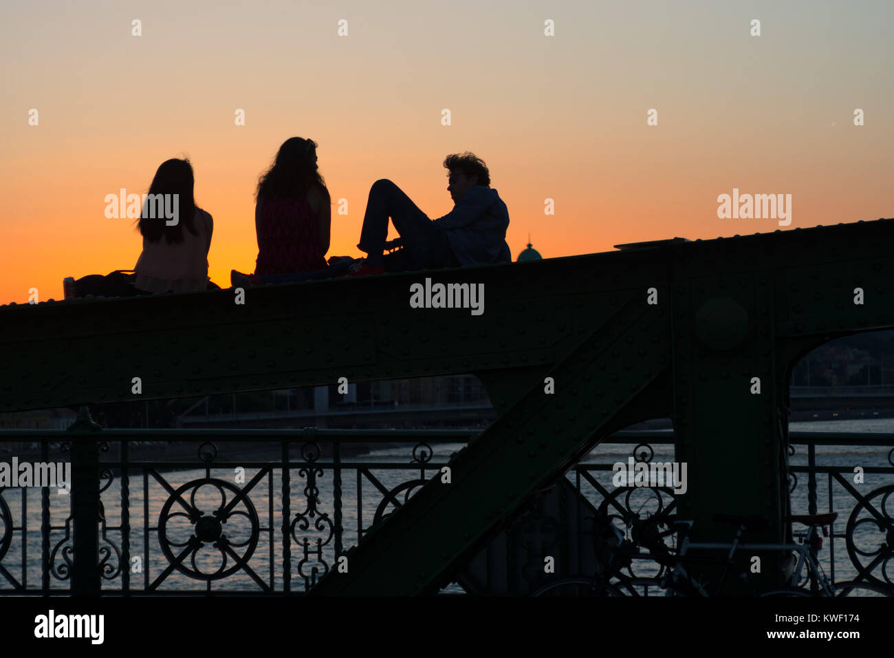 Silhouetten der Baum Jugendlichen sitzt und spricht auf Brücke Strahl Stockfoto