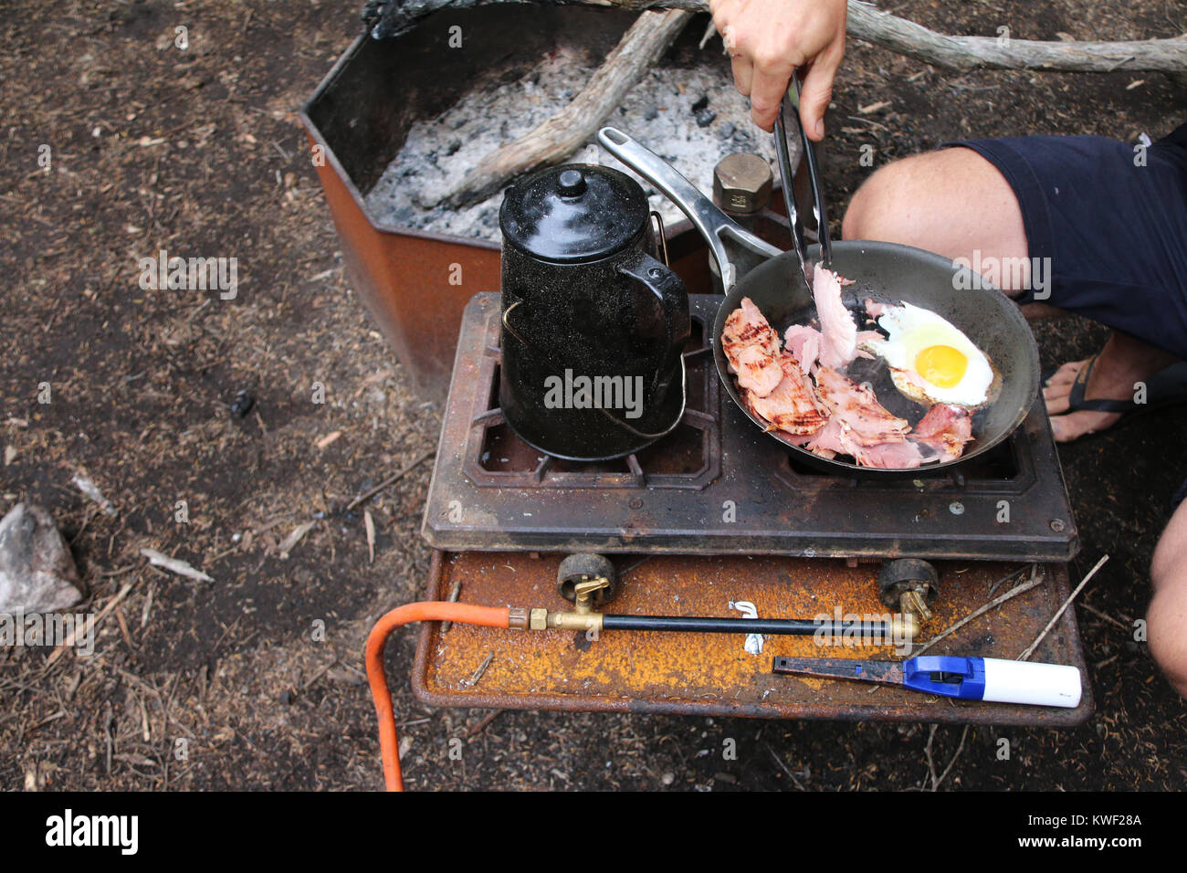 Camping: Mann kochen Speck und Eier zum Frühstück auf der Kraftstoff Herd am Campingplatz in Australien. Stockfoto
