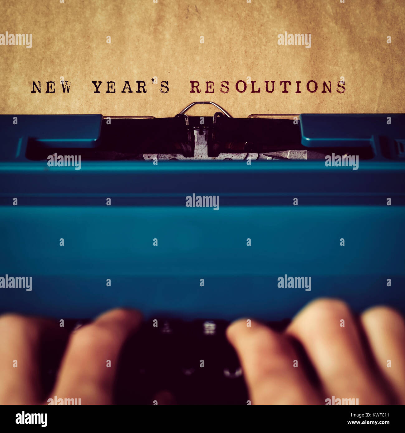 Nahaufnahme von einem Mann Maschinenschreiben den Text neue Jahre Auflösungen in einem gelblichen Papier mit einem blauen retro Schreibmaschine Stockfoto