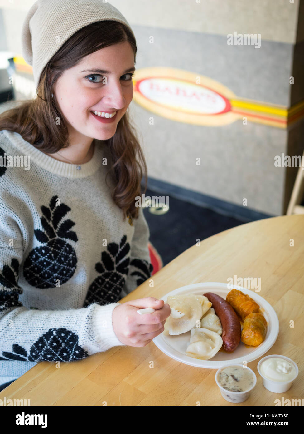 Eine hübsche Brünette Mädchen genießt eine Platte mit Perogies, Kohlrouladen, und smokie von Baba's Homestyle Perogies in Saskatoon, Saskatchewan, Kanada. Stockfoto