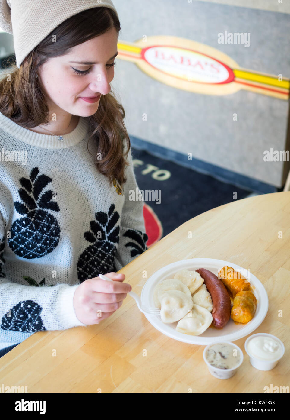 Eine hübsche Brünette Mädchen genießt eine Platte mit Perogies, Kohlrouladen, und smokie von Baba's Homestyle Perogies in Saskatoon, Saskatchewan, Kanada. Stockfoto