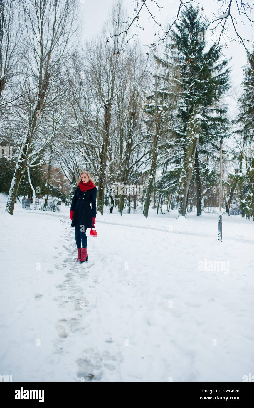 Blonde Mädchen in roten Schal und Mantel Wandern im Park im Winter Tag. Stockfoto