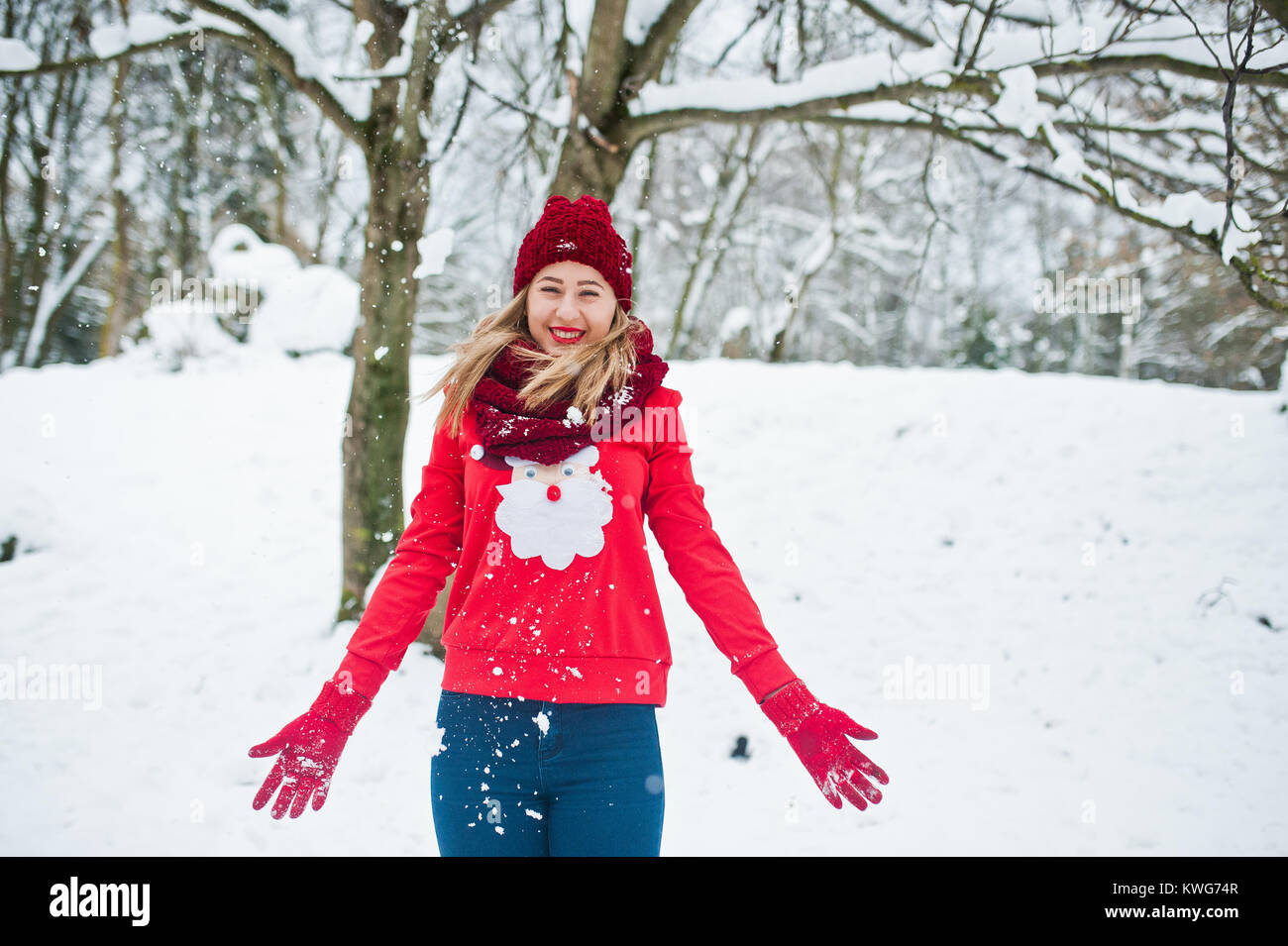 Blonde Mädchen in roten Schal, Mütze und weihnachtsmänner Pullover posiert im Park im Winter Tag. Stockfoto