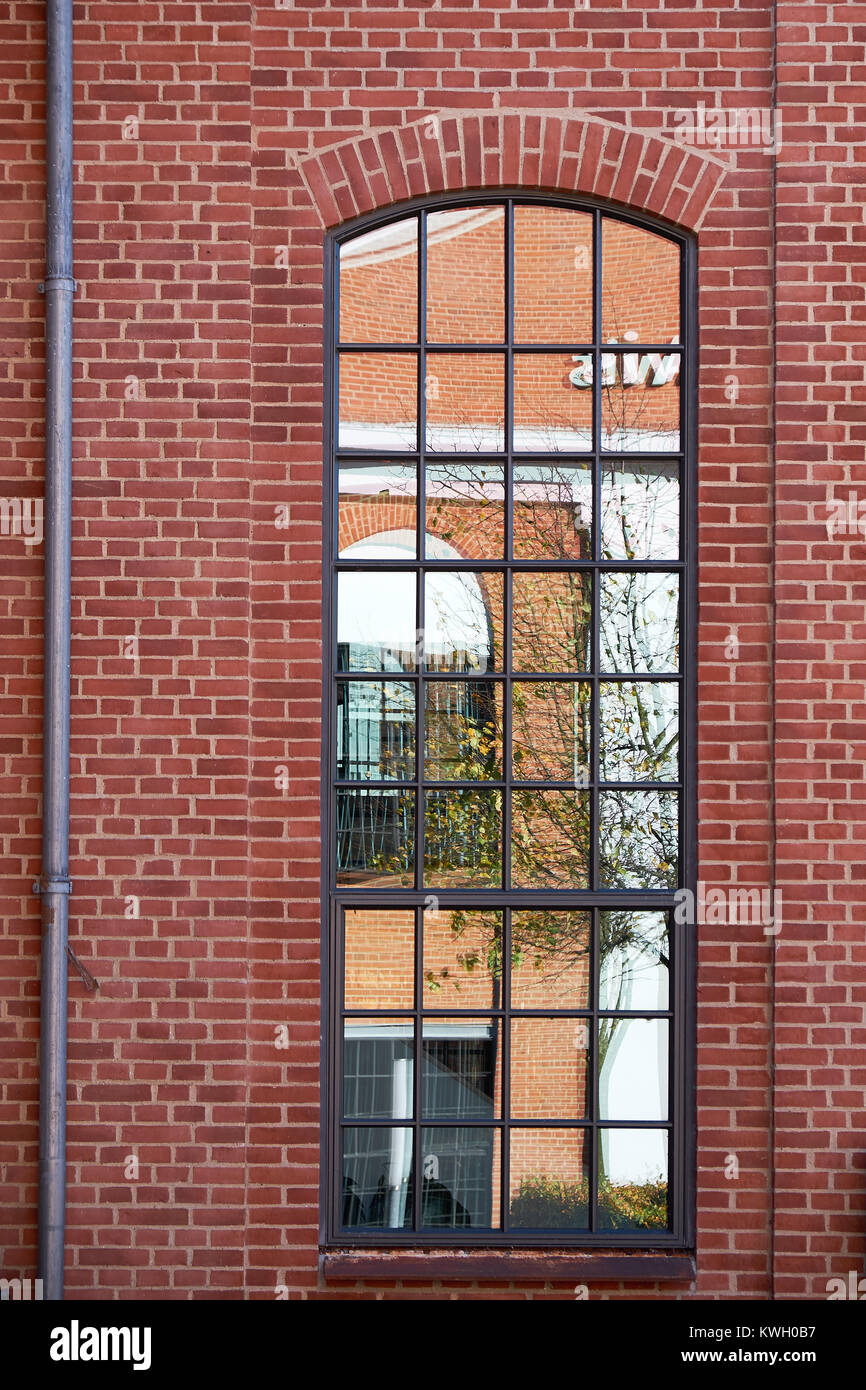 Hohen Bogen format Metall Scheune Stil Fenster mit kleinen Verglasung Muster, in einem roten Backsteinfassade Stockfoto