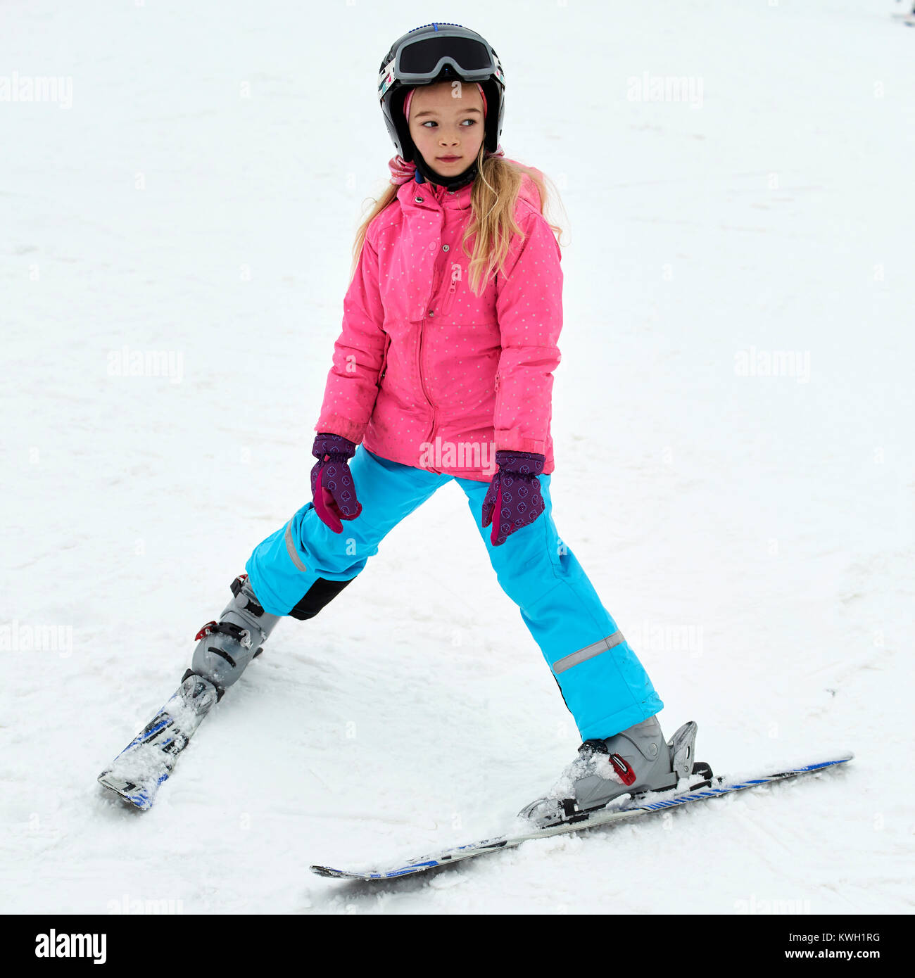 Kind Skifahren in den Bergen. Mädchen in bunten Anzug und Helm Skifahren lernen. Wintersport für Familien mit jungen Kindern. Kids Ski Lektion i Stockfoto