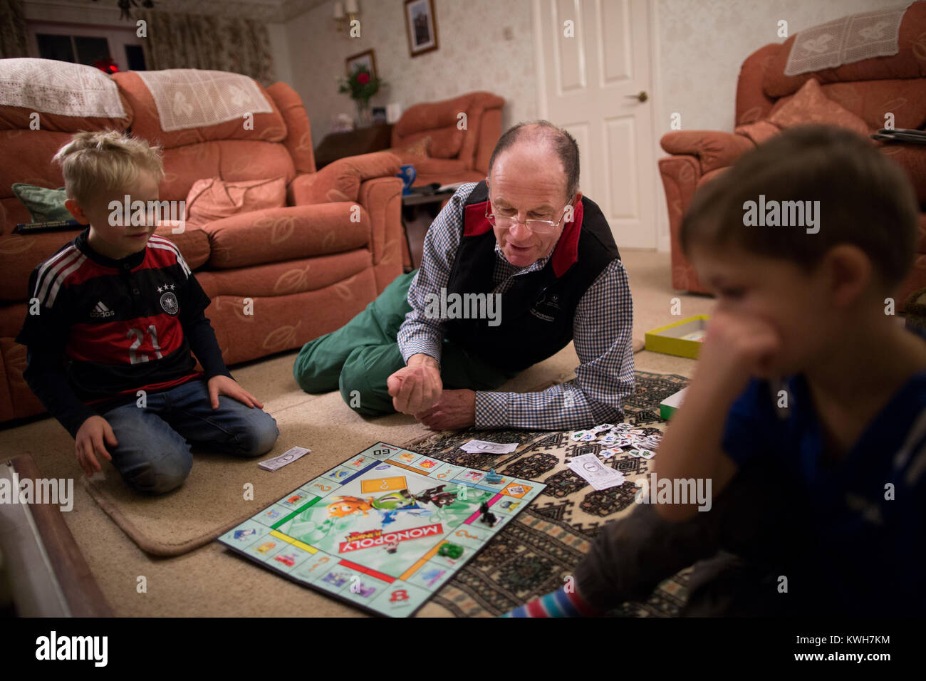 Ein grossvater Spielen Monopoly, Familie Brettspiel, über die Festtage mit seiner beiden Enkel im Vereinigten Königreich Stockfoto