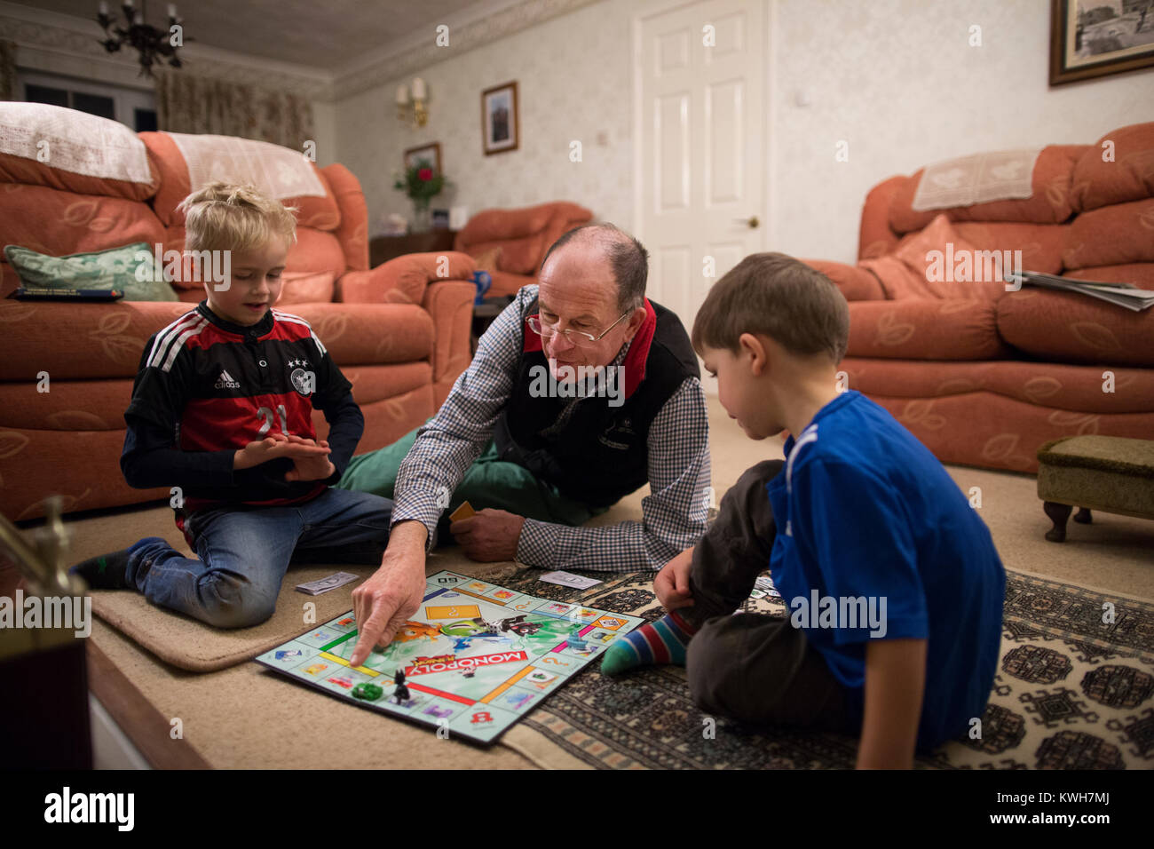 Ein grossvater Spielen Monopoly, Familie Brettspiel, über die Festtage mit seiner beiden Enkel im Vereinigten Königreich Stockfoto