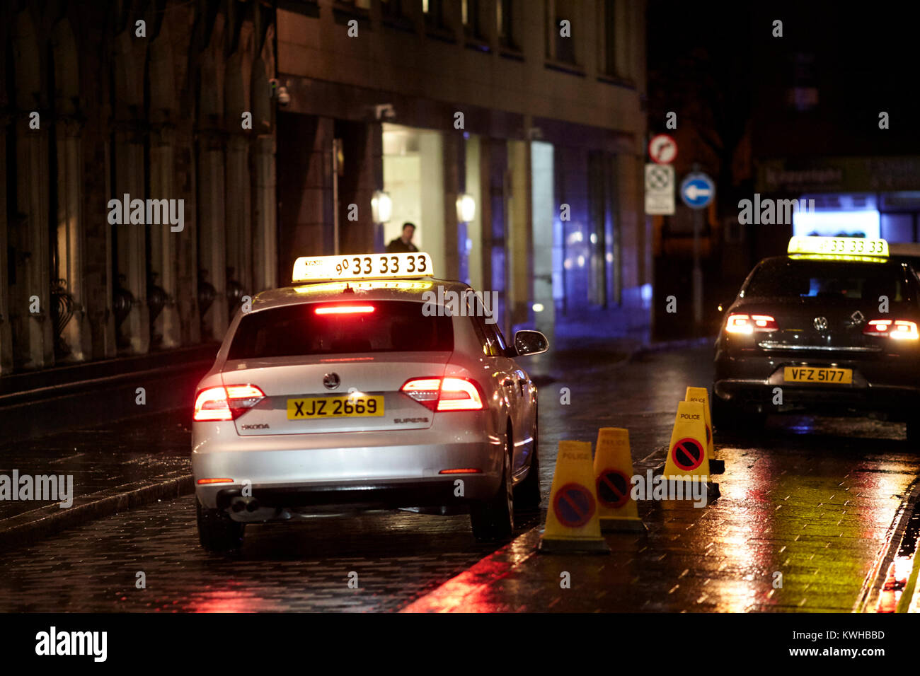 Taxis geparkt außerhalb Pub auf der Straße auf einem nassen und windigen Nacht in Belfast Nordirland UK Stockfoto