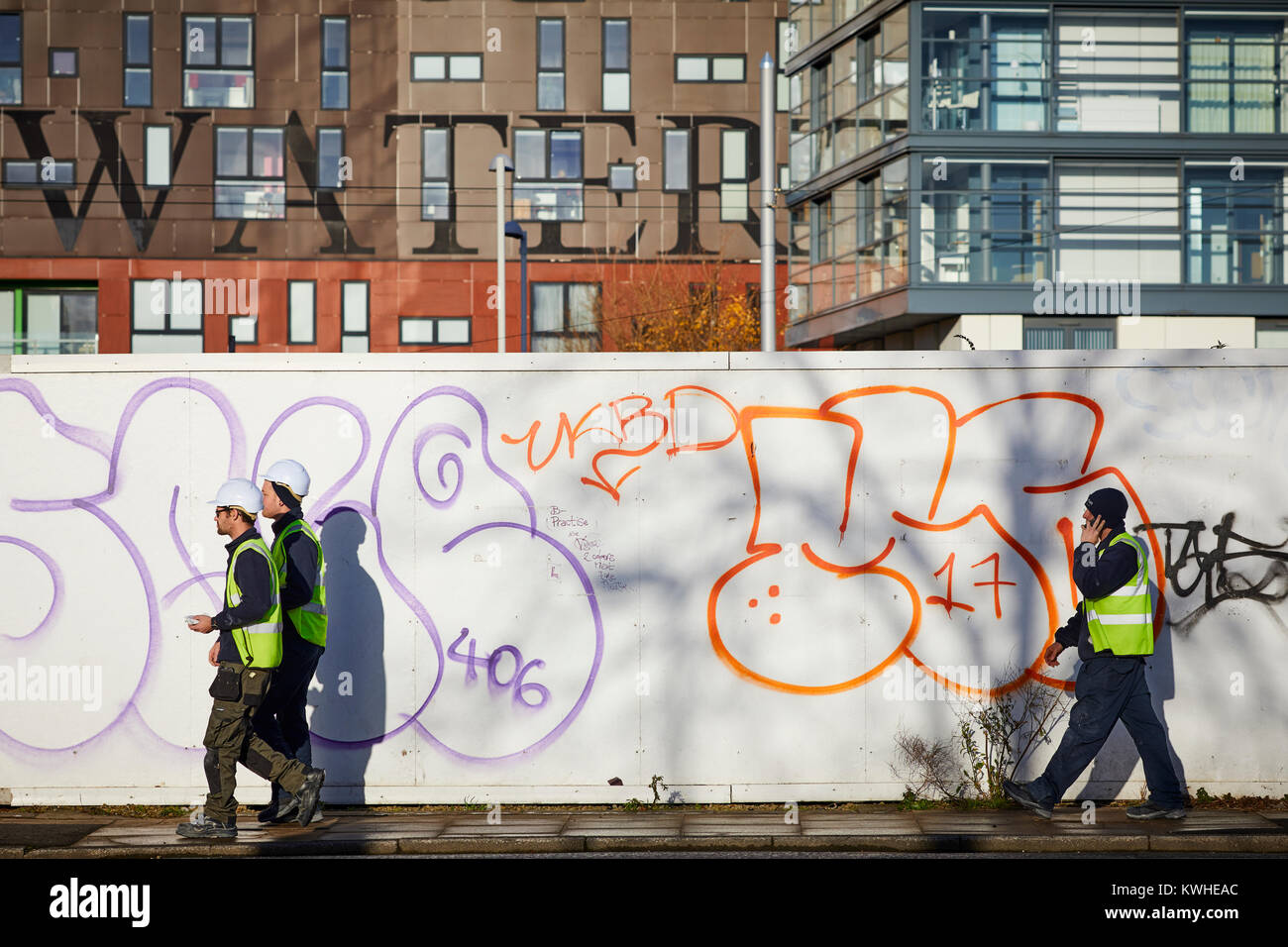 Graffiti'', Spritzlackiert throwups Streetart auf Development Holding Boards in Islington, East Manchester Arbeiter in Sicherheit pep Kleidung Stockfoto