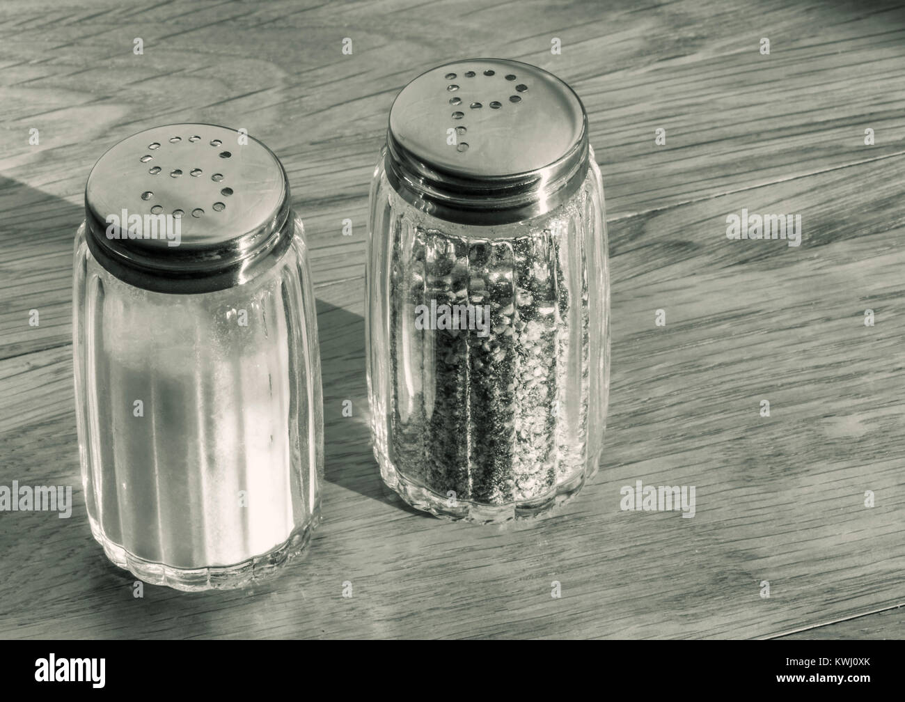 In der Nähe von Glas Salz- und Pfefferstreuer oder Salz- und Pfefferstreuer auf einem Holztisch. Stockfoto