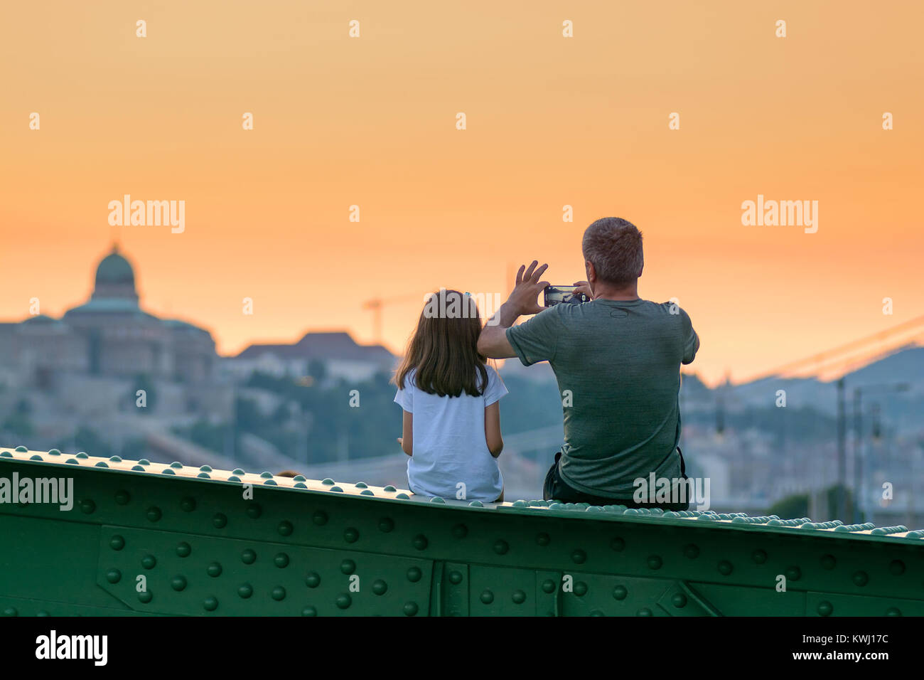 Vater und Tochter sitzen und das Stadtbild bei Sonnenuntergang Stockfoto