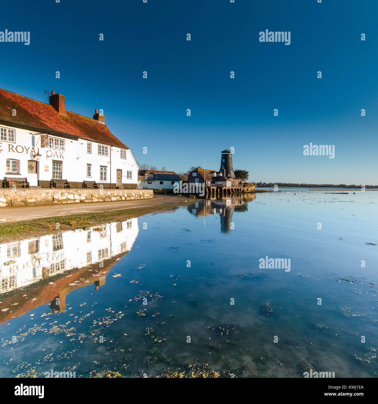 Langstone Hafen mit Mühle und Royal Oak im Winter morgens bei Sonnenaufgang mit hellen Wintersonne und Flut - quadratische Format Stockfoto