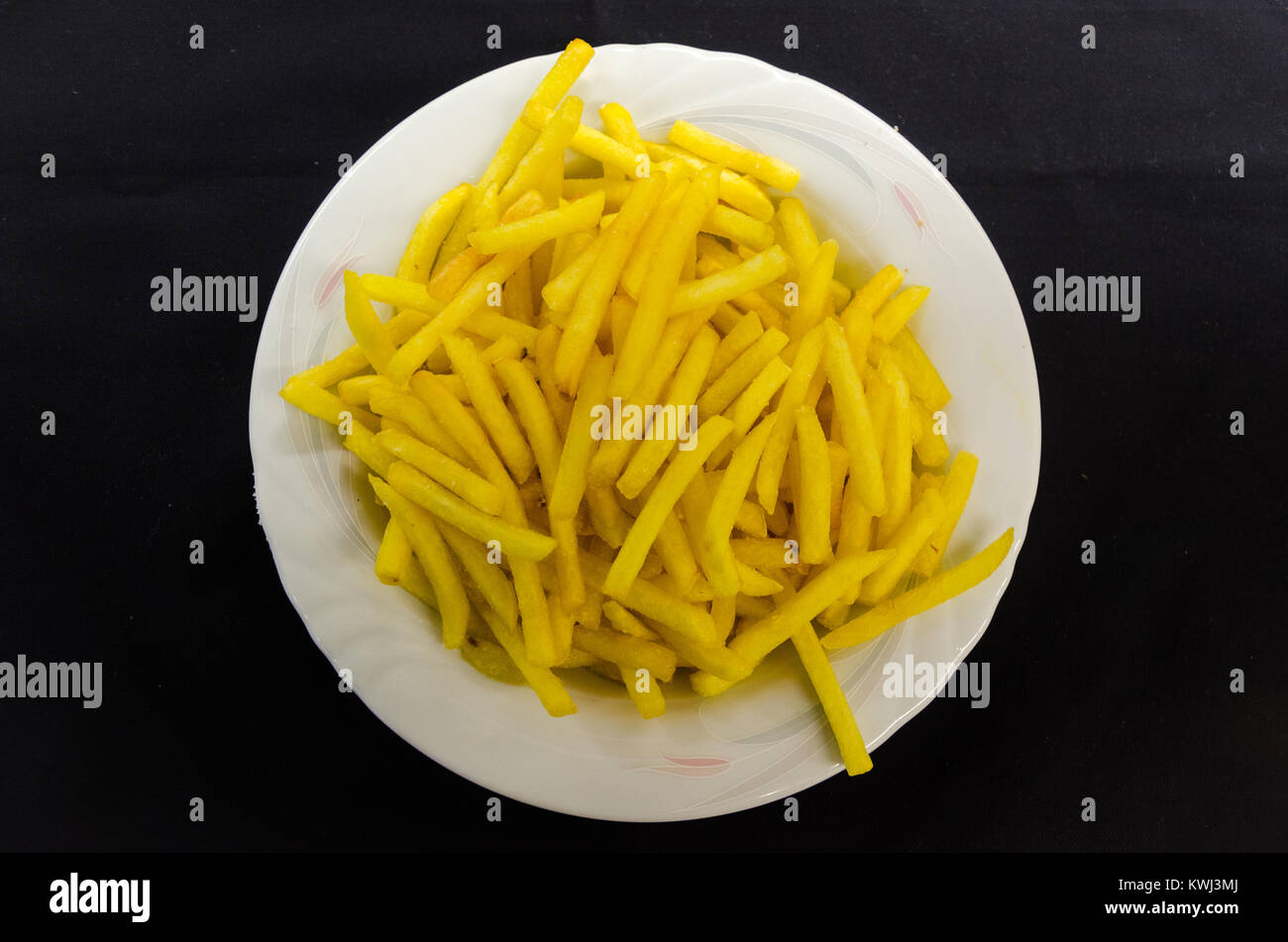 Pommes Frites auf einer weißen Platte über schwarzen Hintergrund. Stockfoto