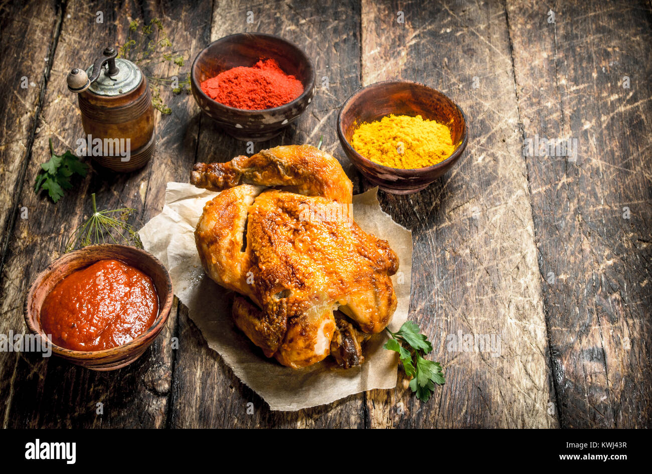 Gebratenes Huhn mit Sauce und Gewürzen. Auf einer hölzernen Tisch. Stockfoto