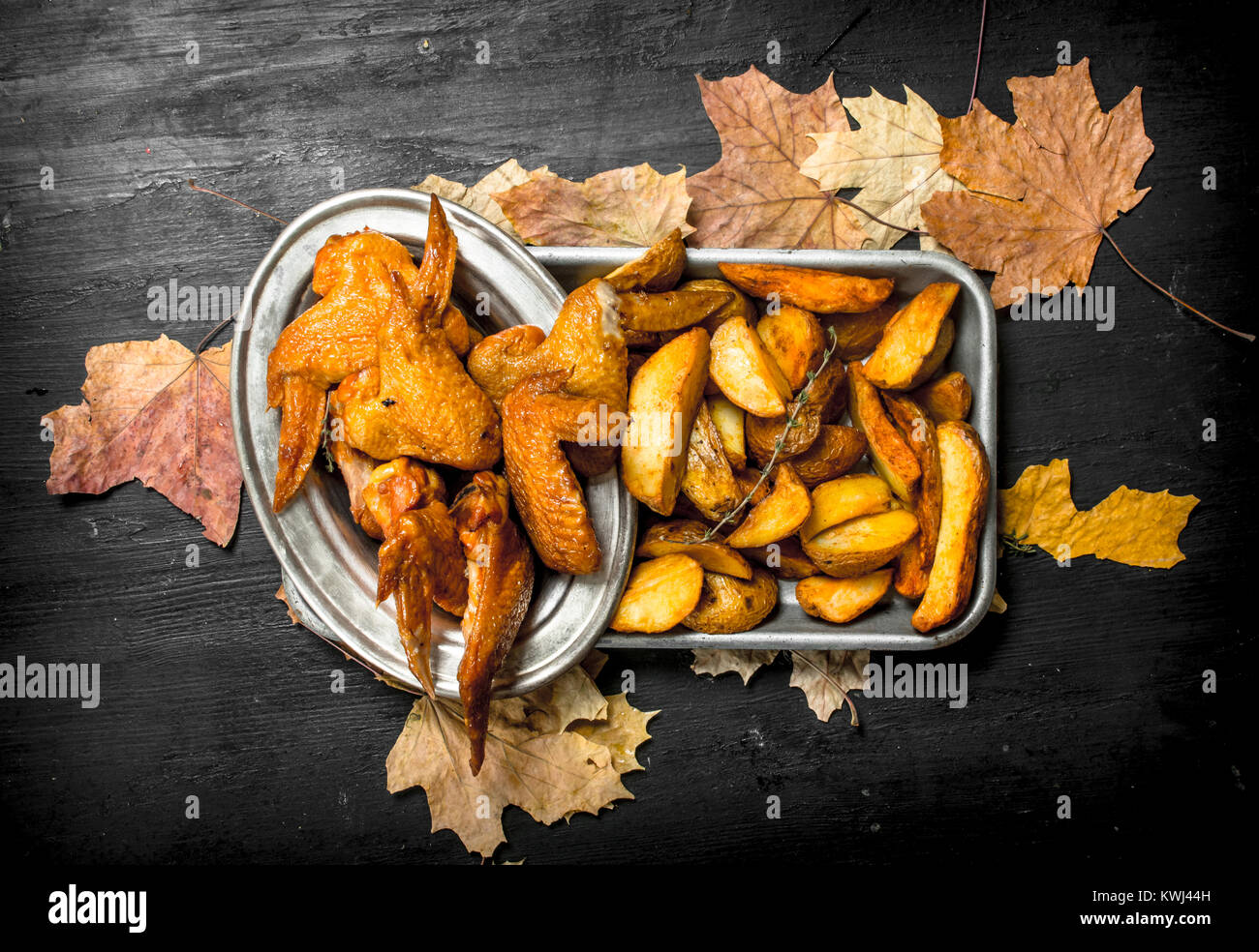 Geräucherte Hühnerflügel mit Bratkartoffeln. Auf der schwarzen Tafel. Stockfoto