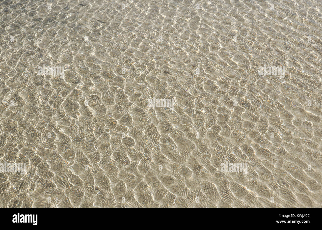 Klares Wasser über Sand unten auf Wind. Sand Wellen Sonnenstrahlen, Stockfoto
