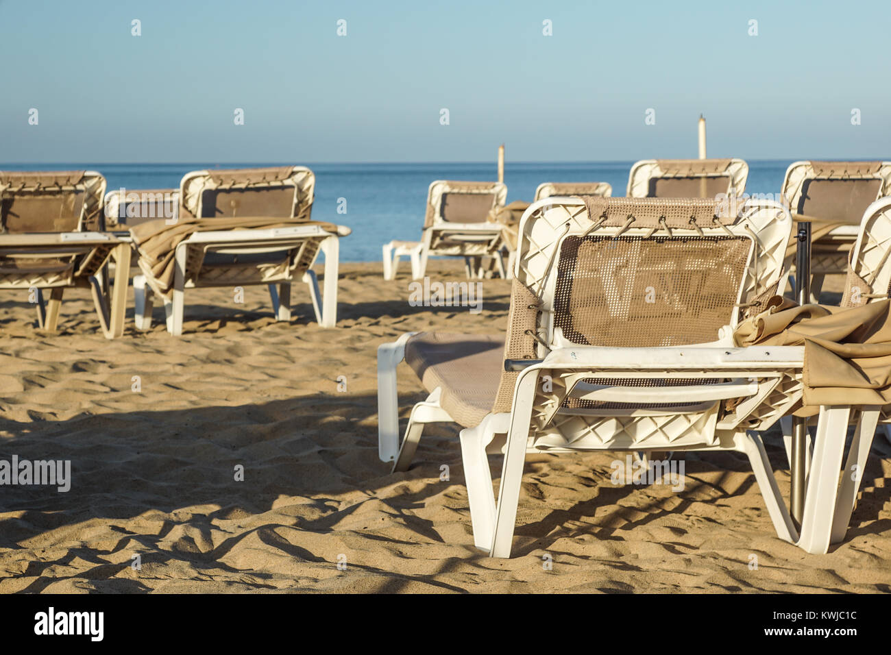 Liegestühle und Sonnenschirme an einem Badeort, die ruhige und entspannte Atmosphäre der Sommerurlaub bei Sonnenuntergang Stockfoto