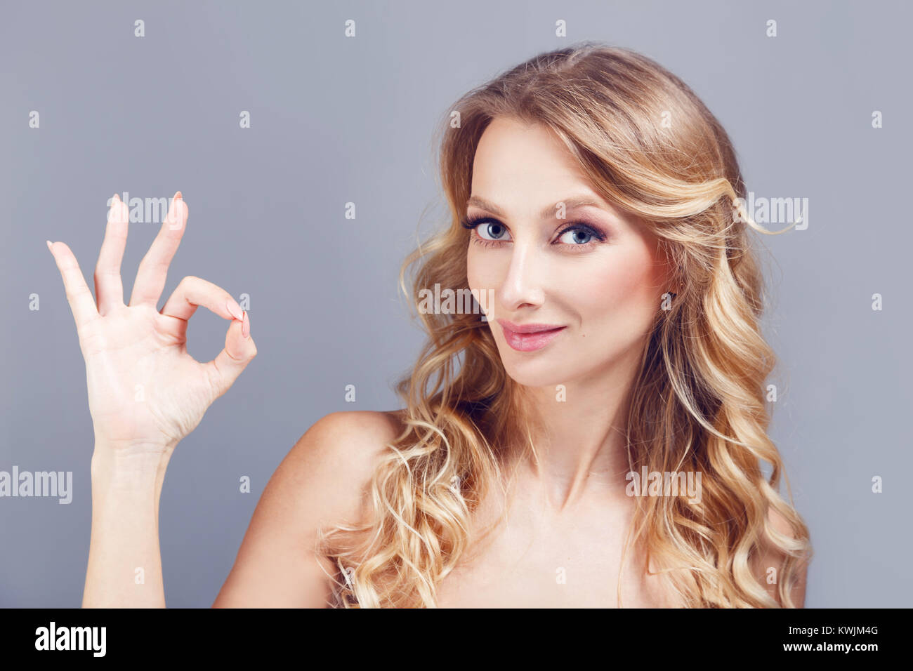 Porträt der Schönen nlondhair Frau, ok, Geste und winking über blau Hintergrund isoliert Stockfoto