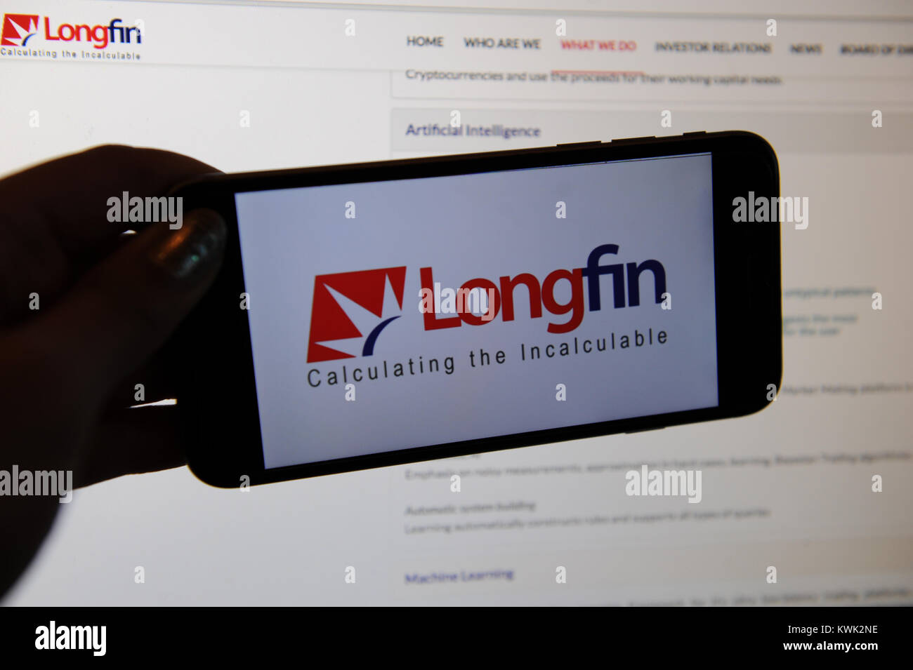 Longfin Logo auf einem Telefon und Ihre Website auf einem PC-Bildschirm. Longfin ist ein kleines-cap fintech Unternehmen mit Hauptsitz in New York Stockfoto