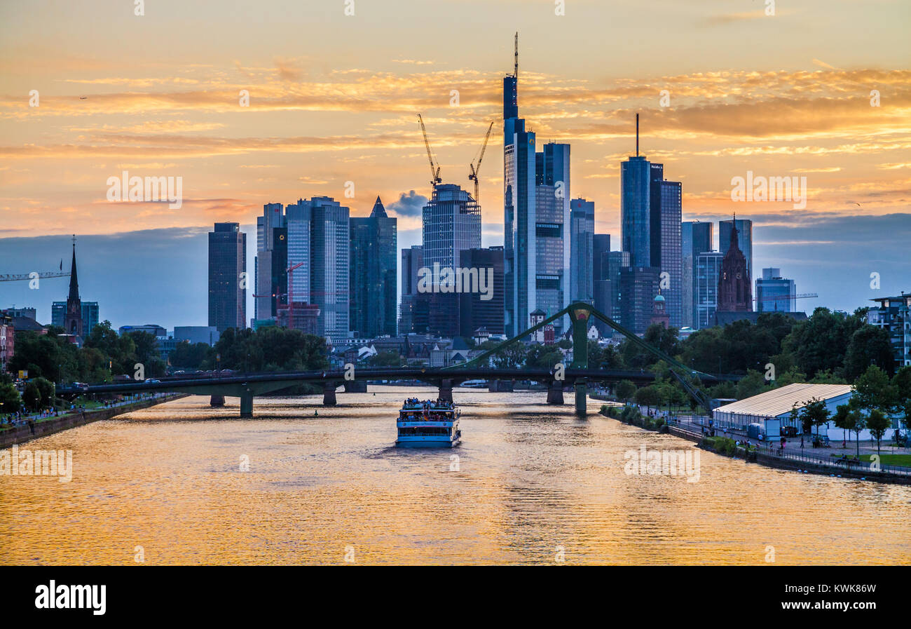 Klassische Panoramablick auf die berühmte Frankfurter Skyline mit dramatischen Wolken und Fahrgastschiff in wunderschönen goldenen post Sonnenuntergang Dämmerung, Deutschland Stockfoto