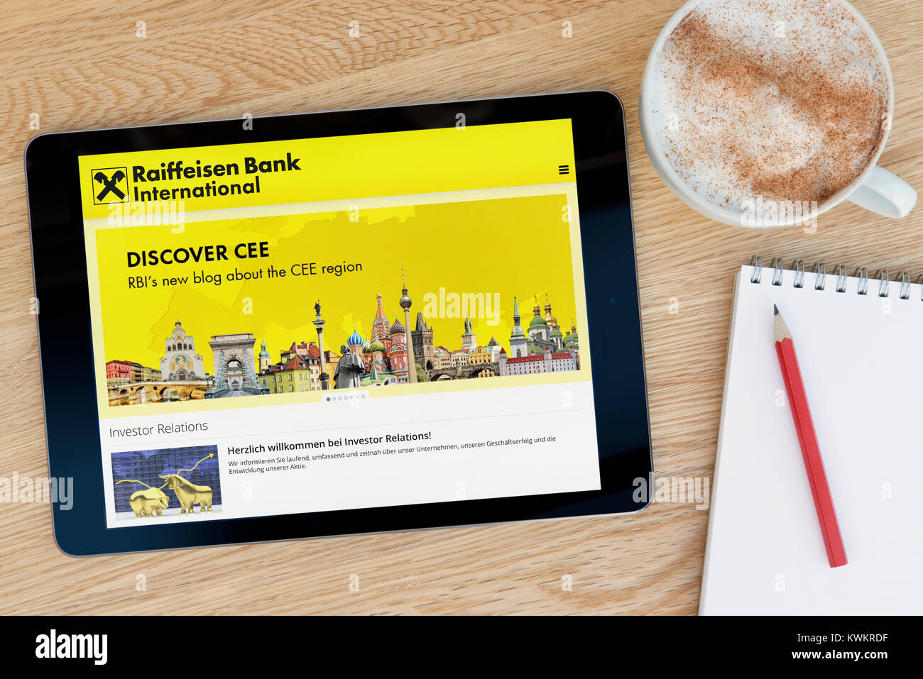 Die Raiffeisen Bank International Website auf einem iPad tablet device, auf einen hölzernen Tisch neben einem Notizblock, Bleistift und Tasse Kaffee (nur redaktionell) Stockfoto